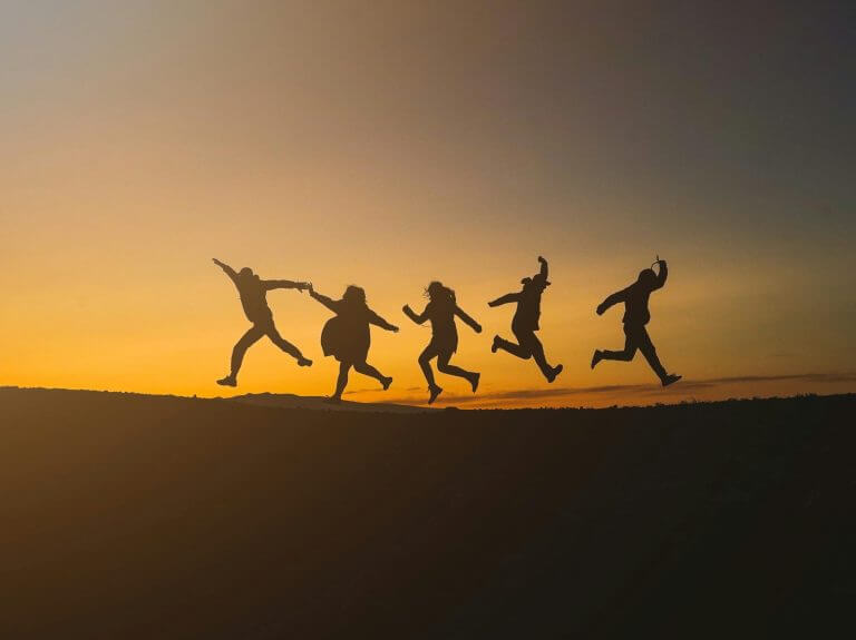 Cinq personnes dansent au coucher du soleil